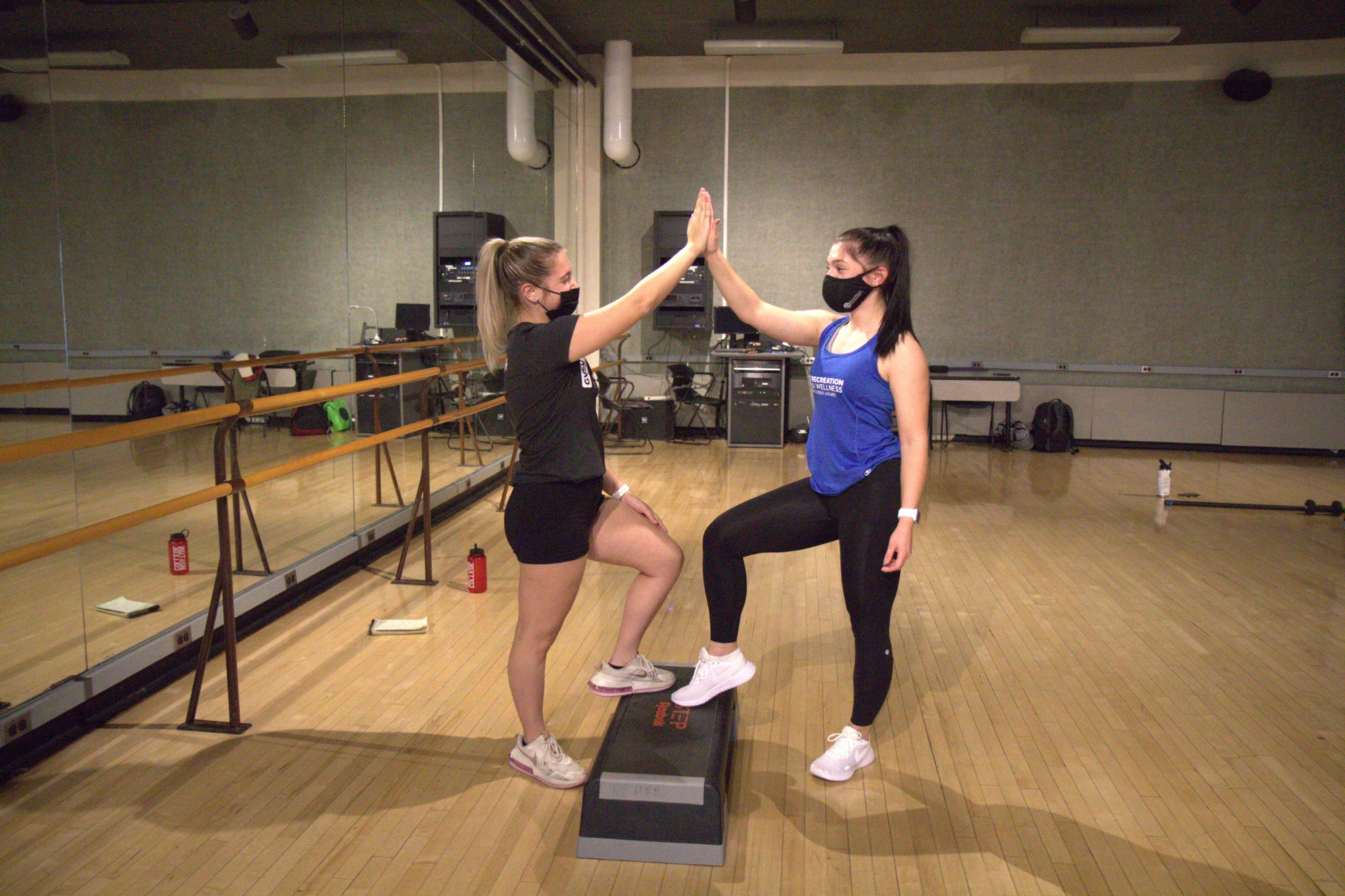 Student and Instructor standing together with their foot on a step high fiving